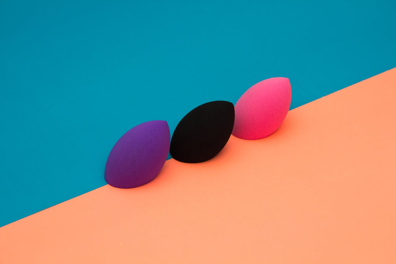 Home Three makeup sponges on a vibrant, split-color background create a striking minimalist composition.