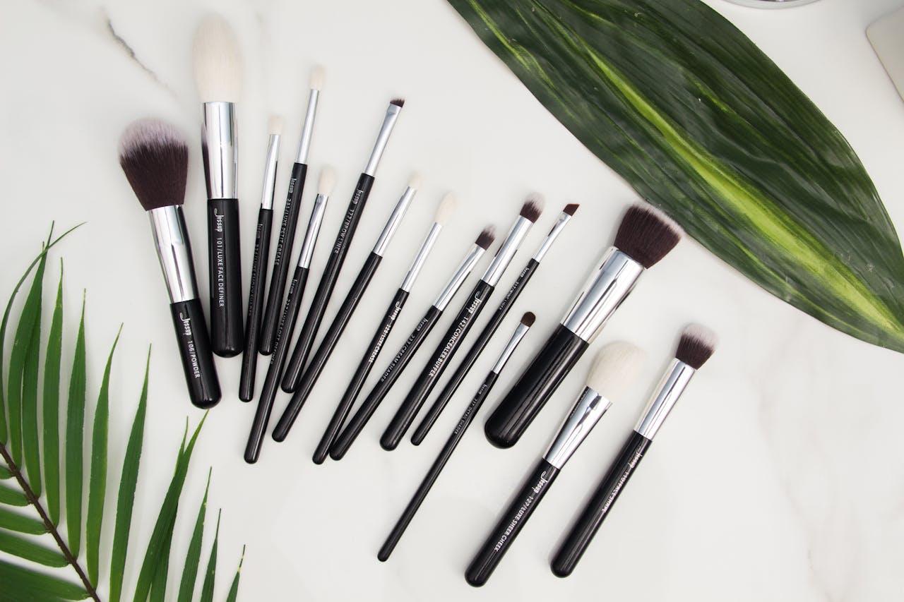 Services Explore a stylish set of makeup brushes laid on a marble surface with green leaves, perfect for beauty enthusiasts.
